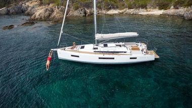 Sun Odyssey 440 anchored in a cove while a couple enjoys the environment.
