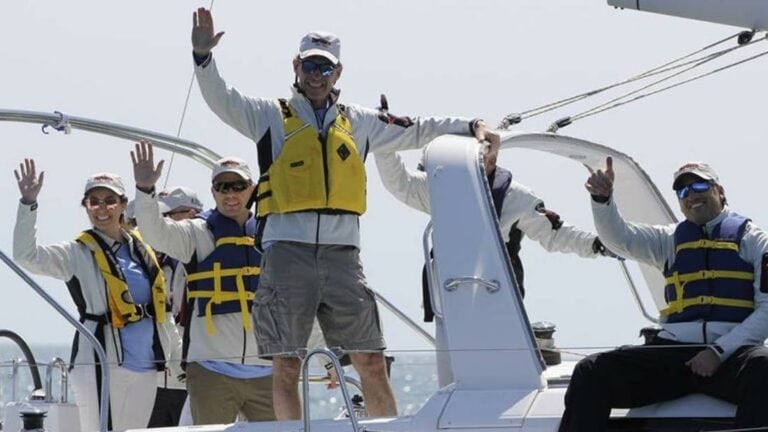 man in yellow lifevest waiving from boat