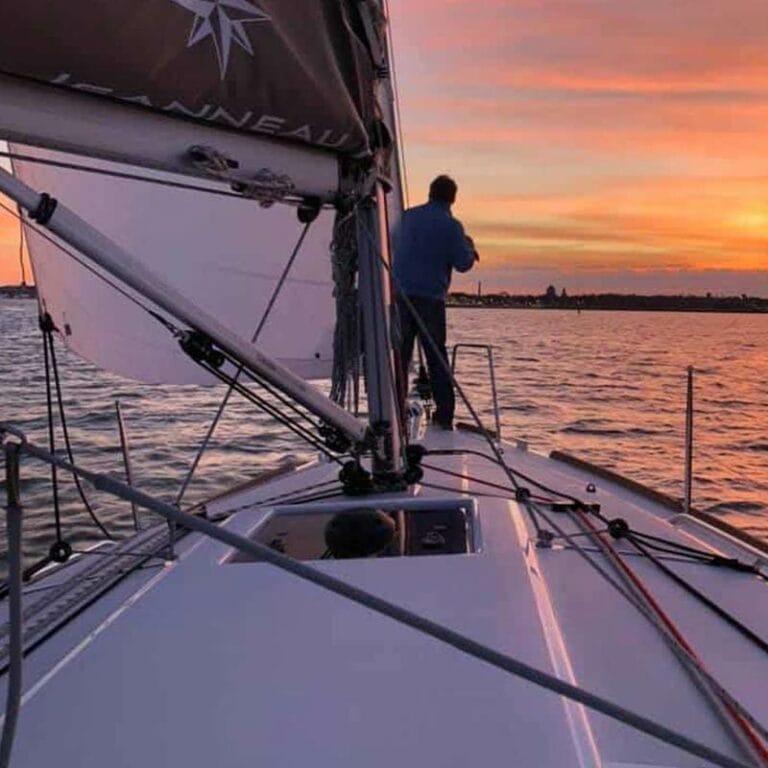 Sailboat enthusiast standing on the bow of a boat at sunset