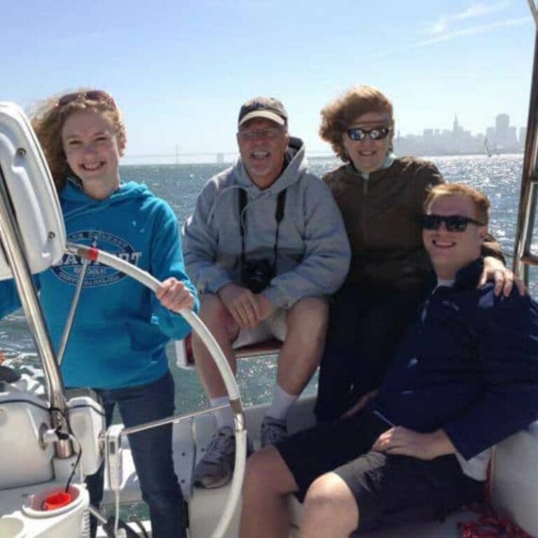 Family posing for a photo at the helm of a sailboat