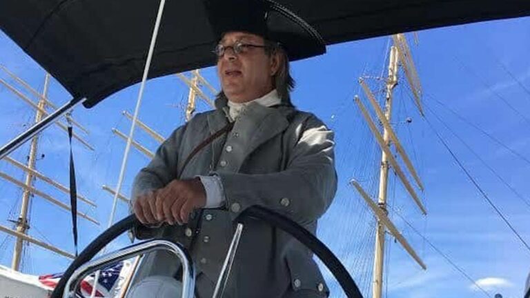 Ben Franklin impersonator standing at a ship's wheel