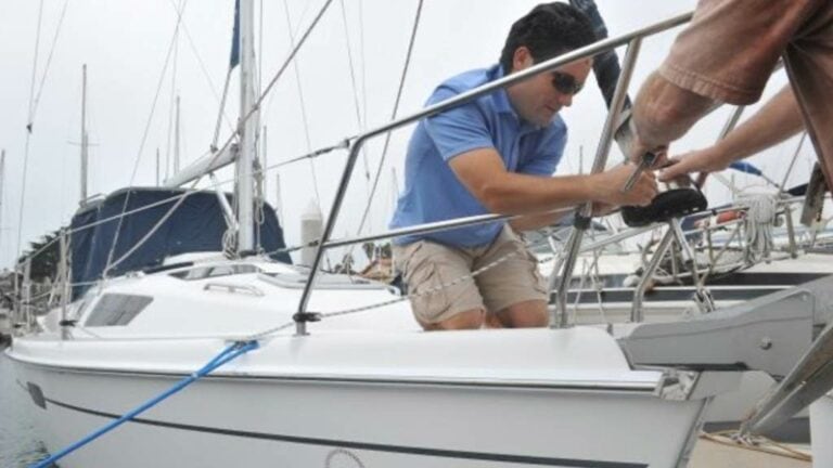 Two people working on a sailboat rigging