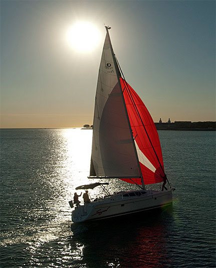Sailboat with red and white sails at sunset