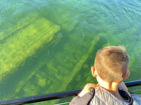 Little boy looking down at Grapeshot wreckage
