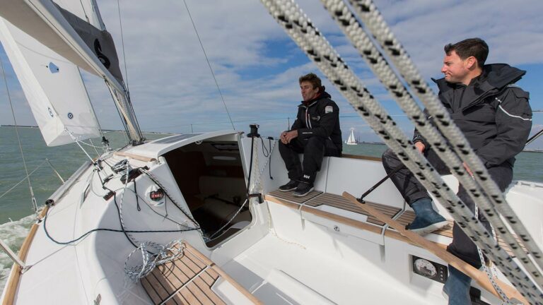 2 Men sitting on the side of a Beneteau First 25 under sail