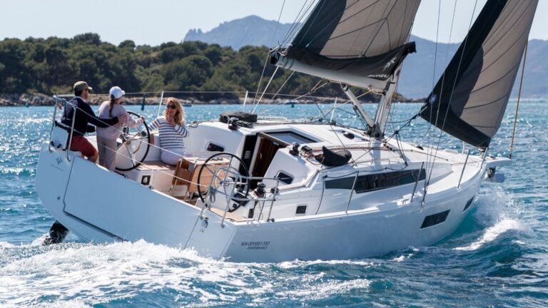 A man, woman, and child sailing on a jeanneau sun odyssey 350.